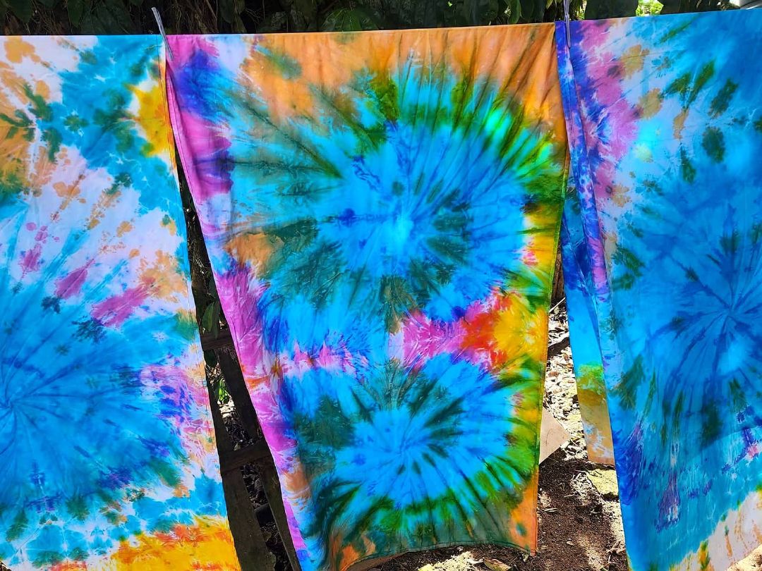 Tie & dye sulus drying on a line outdoors in blue, pink and green spiral patterns